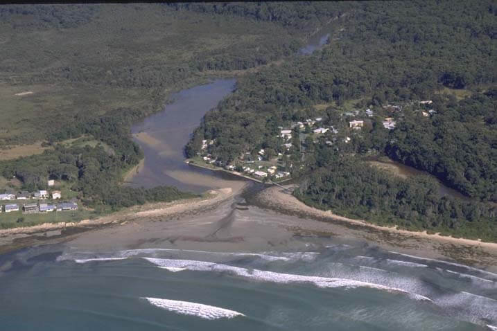 A view of Arrawarra Creek surrounded by a coastal town and the beach in the foreground