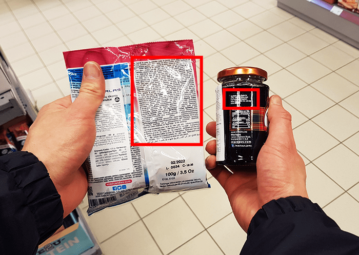 Hands holding a pack of sweet next to a jam jar.